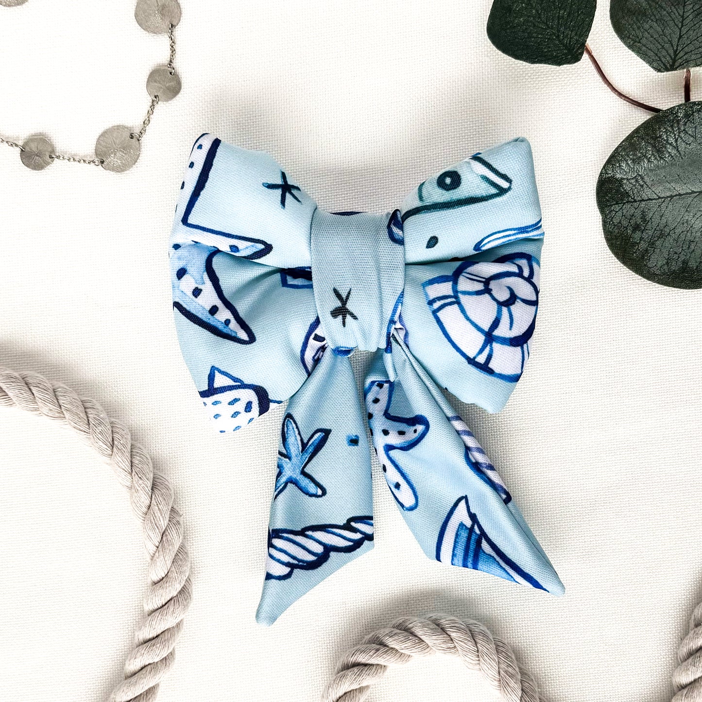 A blue dog sailor bow with dark blue and white seashells.