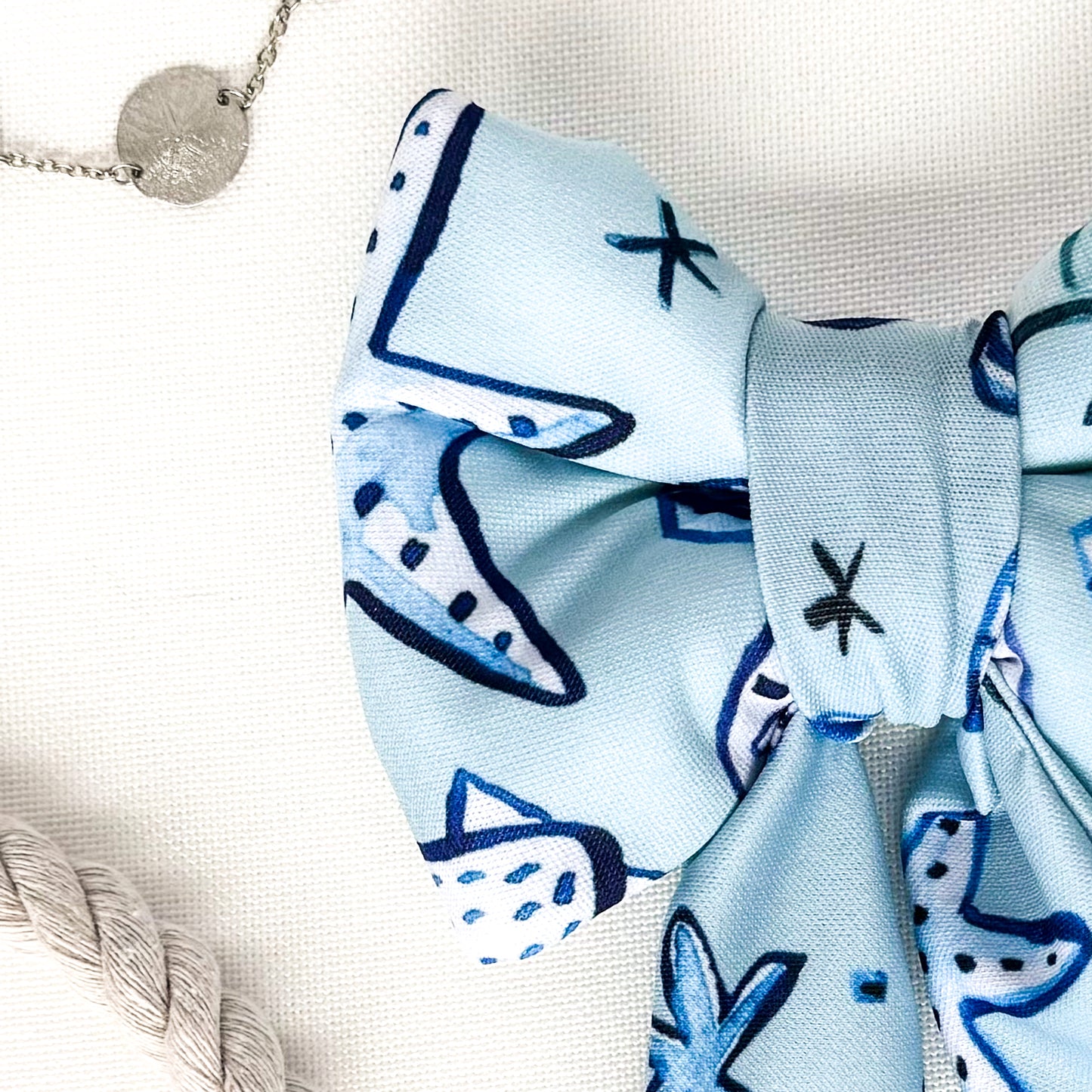 Close up view of a blue dog sailor bow with dark blue and white seashells.