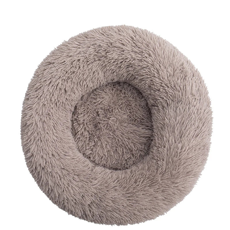 A beige plush dog bed shaped like a donut, offering a comfortable and secure space for small dogs to curl up and relax.