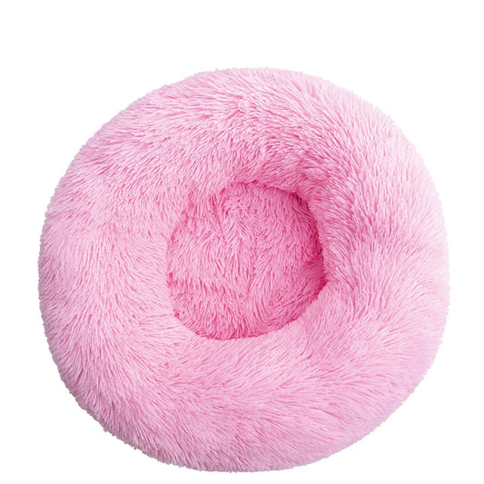 A dark pink plush dog bed shaped like a donut, offering a comfortable and secure space for small dogs to curl up and relax.
