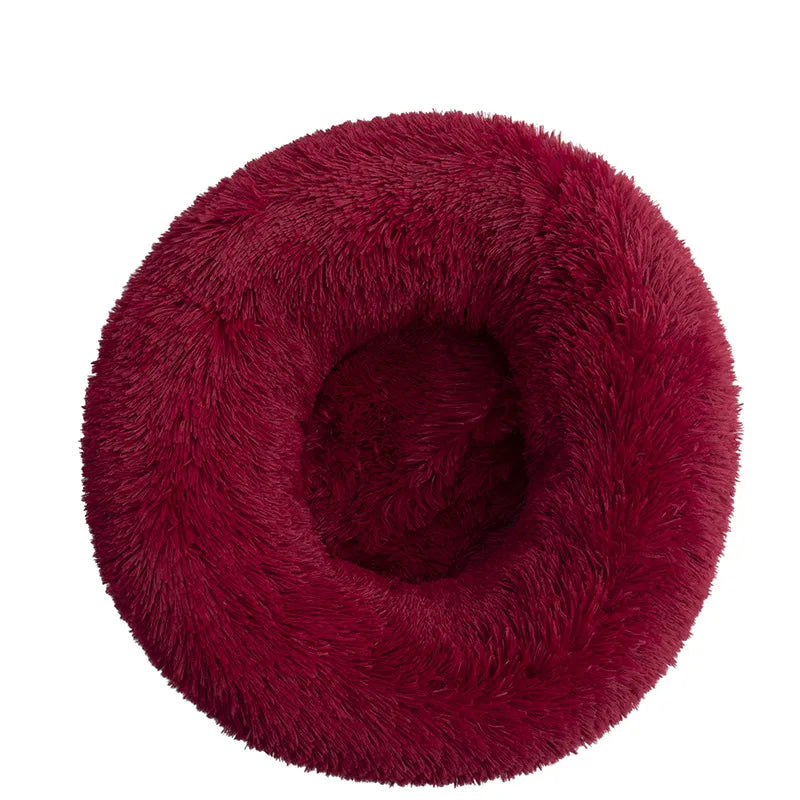 A red plush dog bed shaped like a donut, offering a comfortable and secure space for small dogs to curl up and relax.