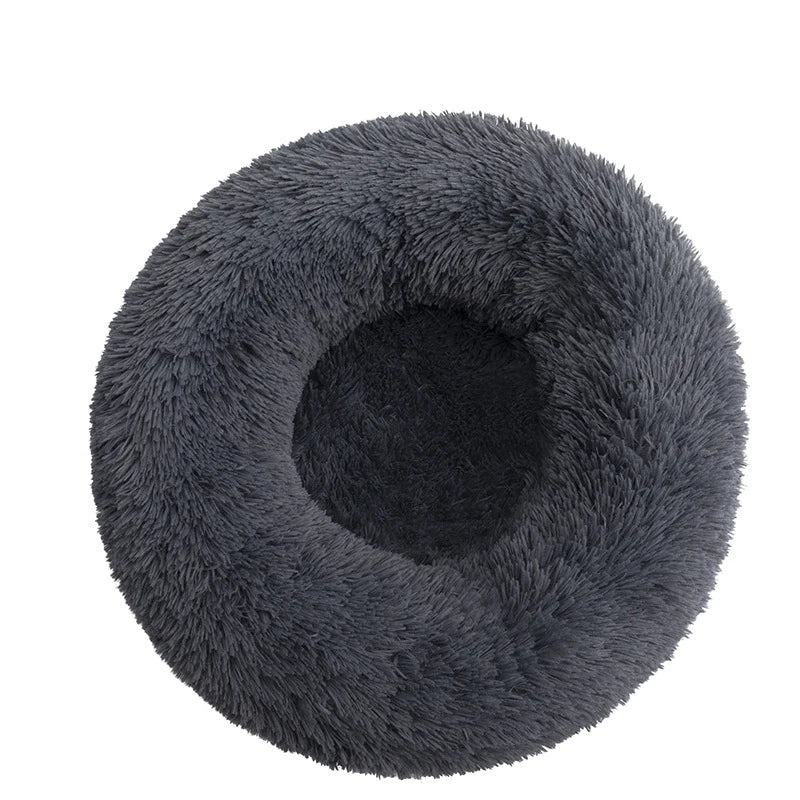 A gray plush dog bed shaped like a donut, offering a comfortable and secure space for small dogs to curl up and relax.
