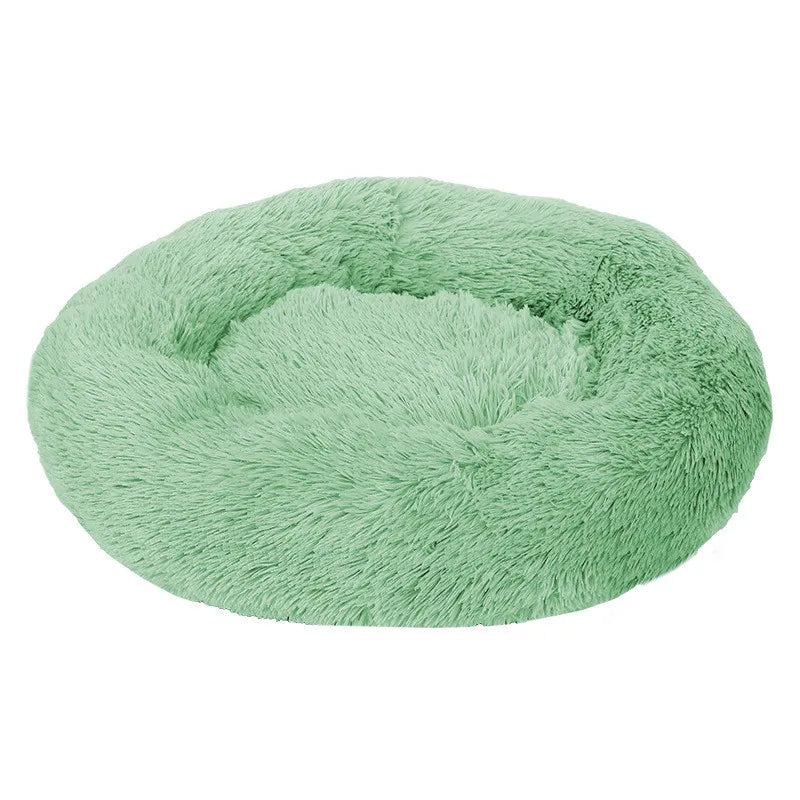 A green plush dog bed shaped like a donut, offering a comfortable and secure space for small dogs to curl up and relax.