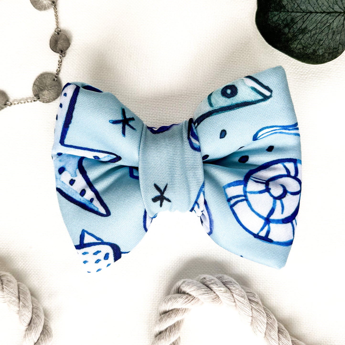 A blue classic dog bowtie with dark blue and white seashells.